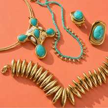 Load image into Gallery viewer, A gold-tone necklace with turquoise stones, a beaded turquoise necklace, a gold statement ring, a gold oval ring, and a gold spiked collar necklace.